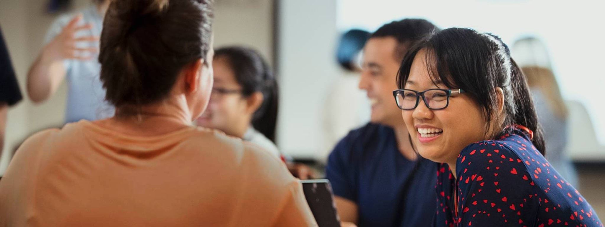 People sitting around a table talking and smiling People sitting around a table talking and smiling