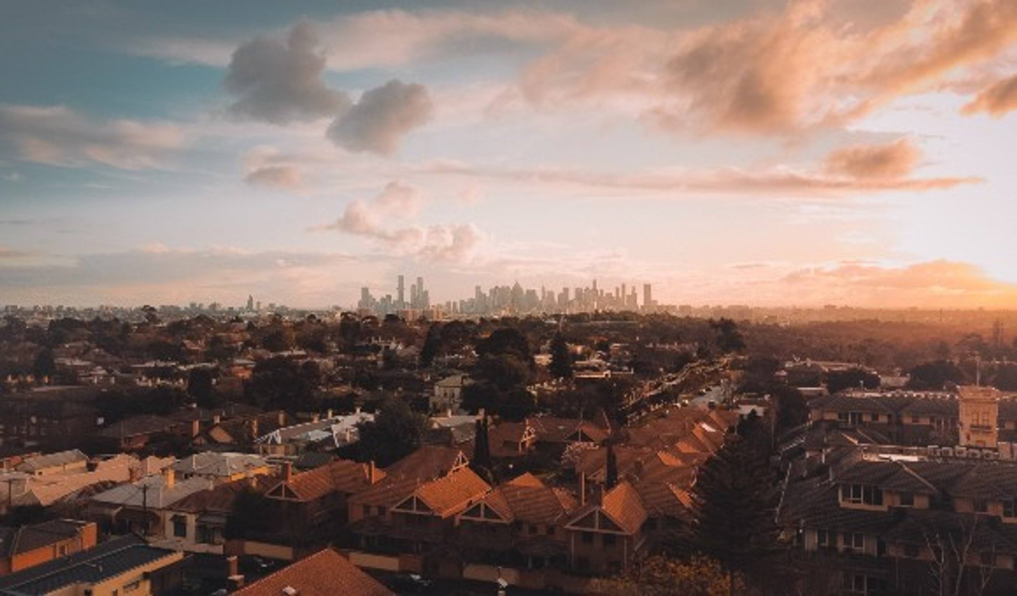 A rooftop photo of Melbourne looking over the roofs of houses and showing the CBD in the distance.
