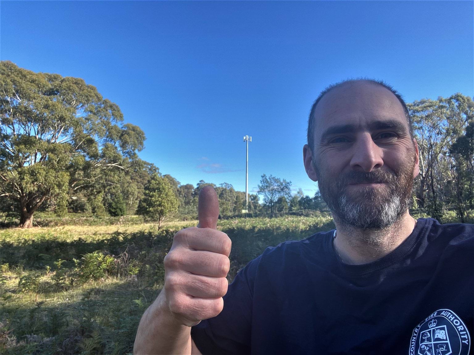Gary Deer Man taking selfie on rural property with his thumb up and mobile phone tower in background