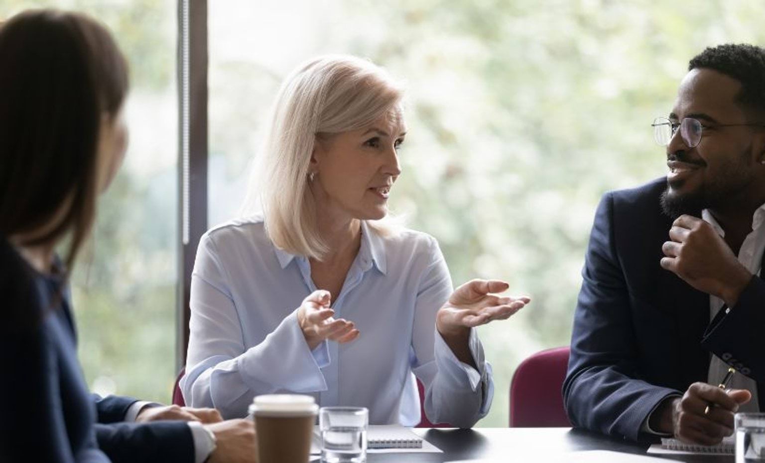 Three people sitting at a meeting room table Three people sitting at a meeting room table