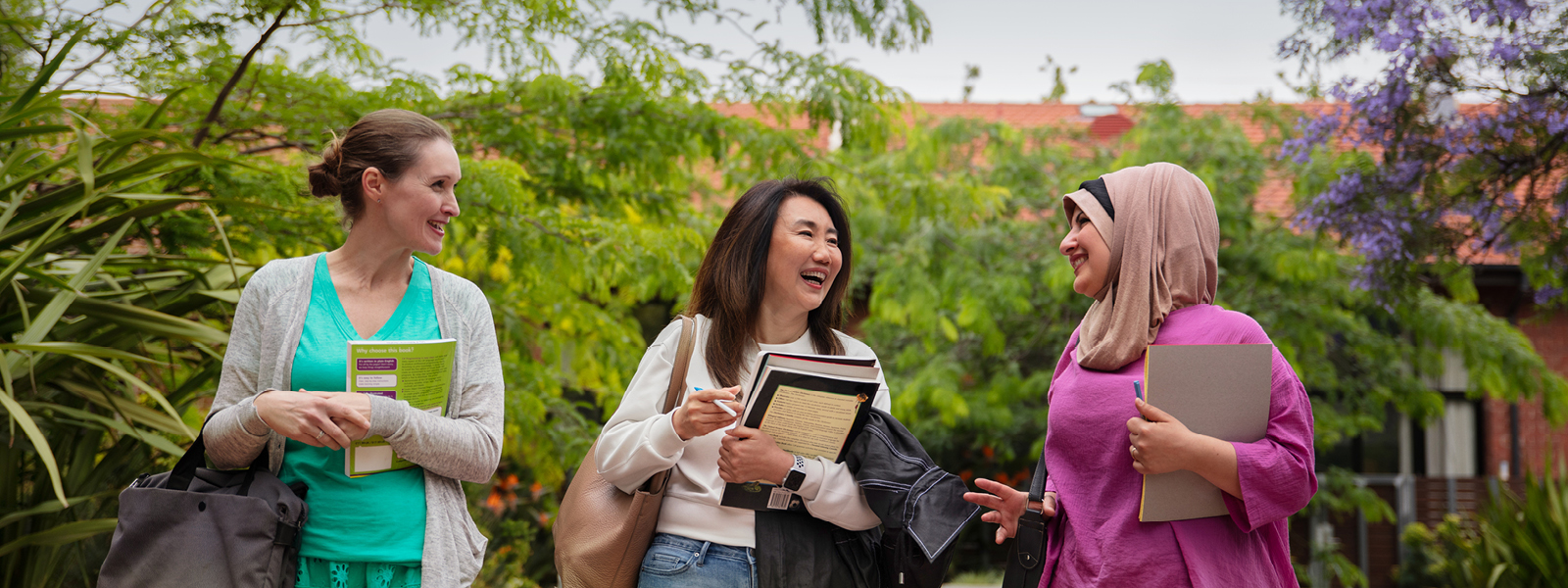 Three students walking next to each other outside, smiling.