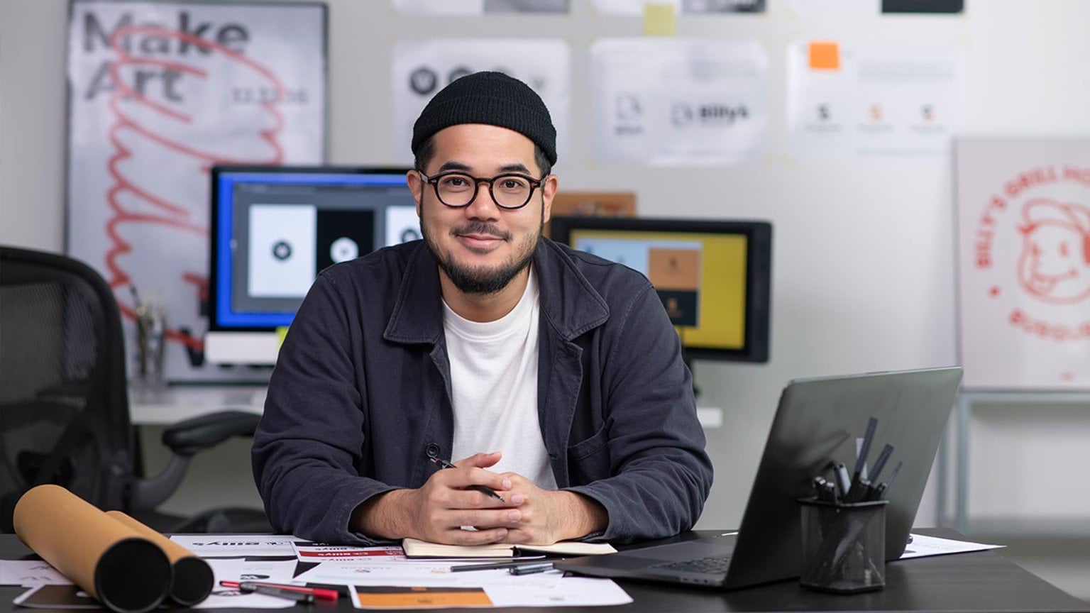 Person at desk in a digital art studio with computer screens in background