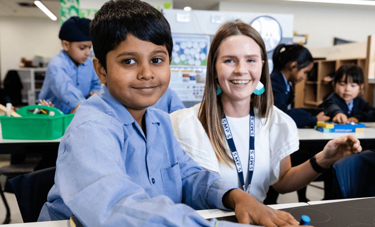 Information for schools A male primary school student in a light blue shirt and a female teacher in a white shirt both smile at the camera.
