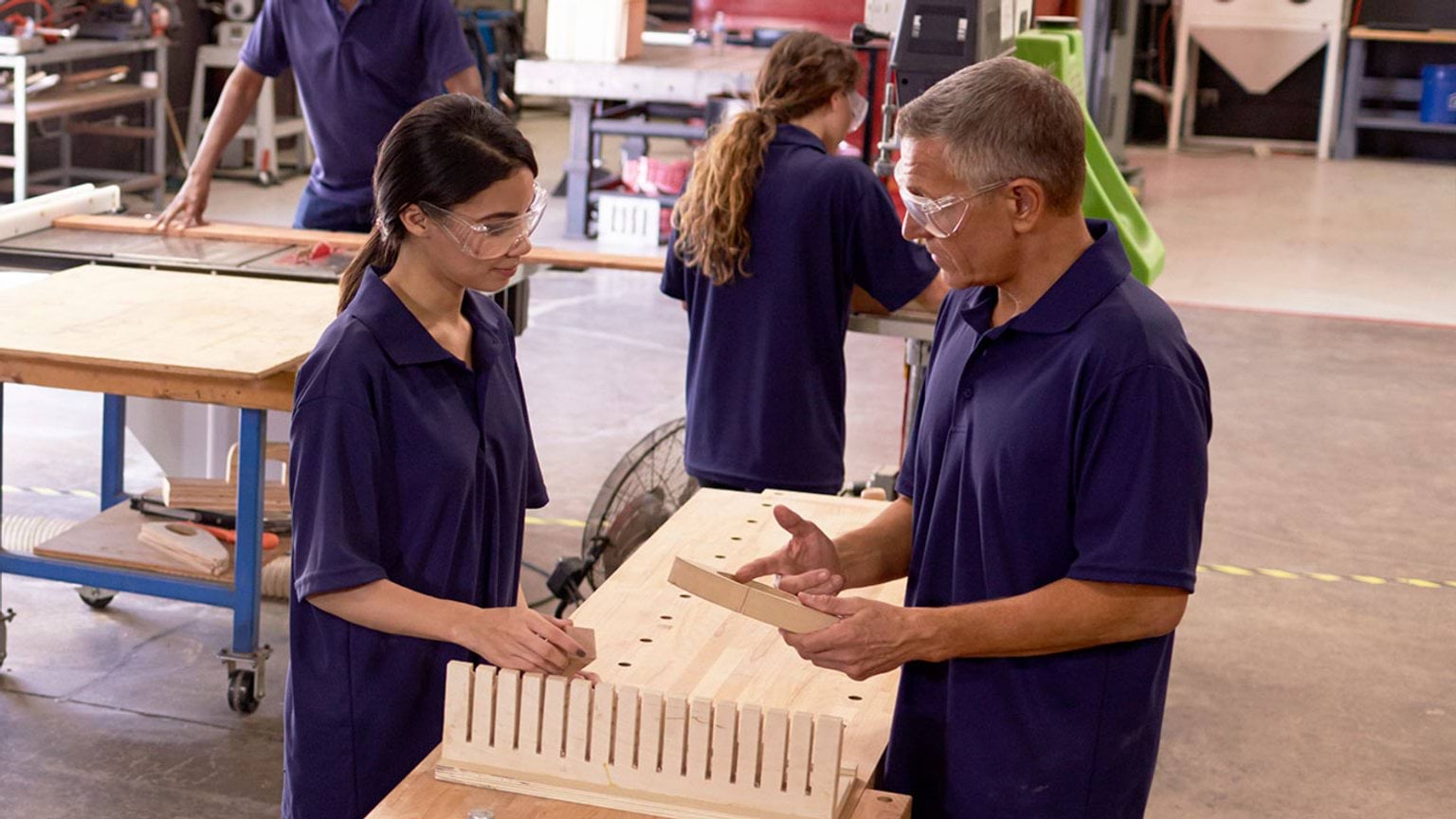 Student learning woodworking with teacher