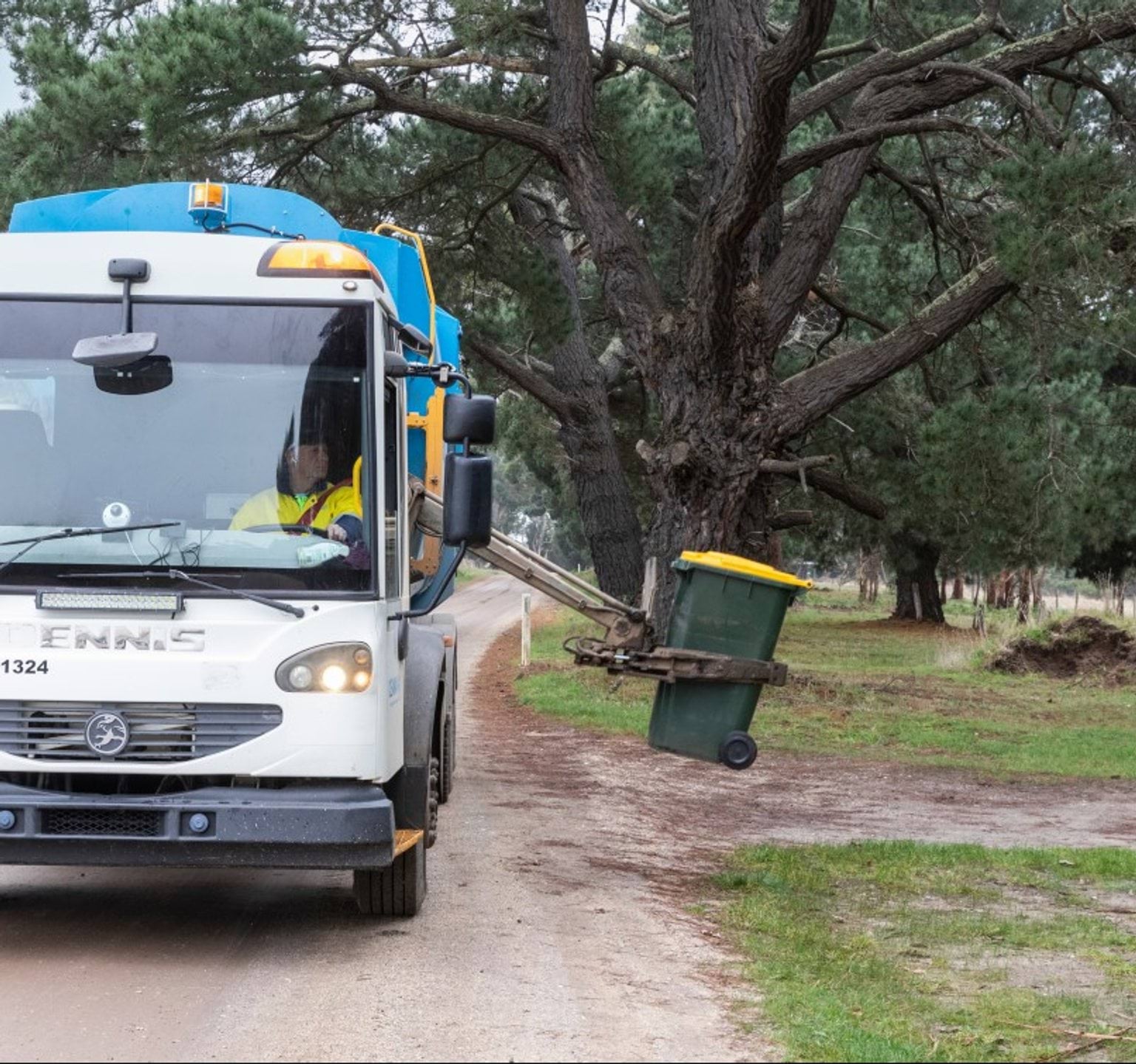 Truck picking up kerbside comingled recycling bin with yellow lid