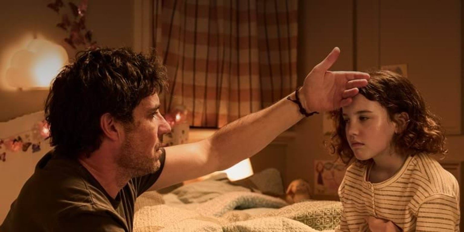 caring father tending to his sick child feeling their forehead for a fever