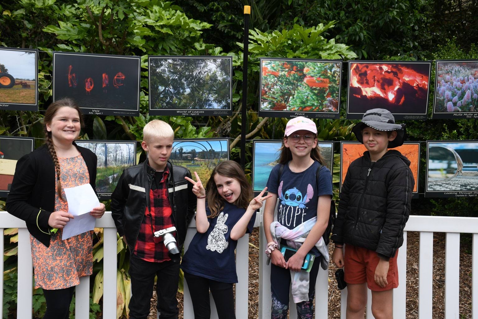 Sarsfiled Snaps by Sarsfield Kids Project Image of children standing in front of Sarsfield photography snaps strung on a fence benhind them