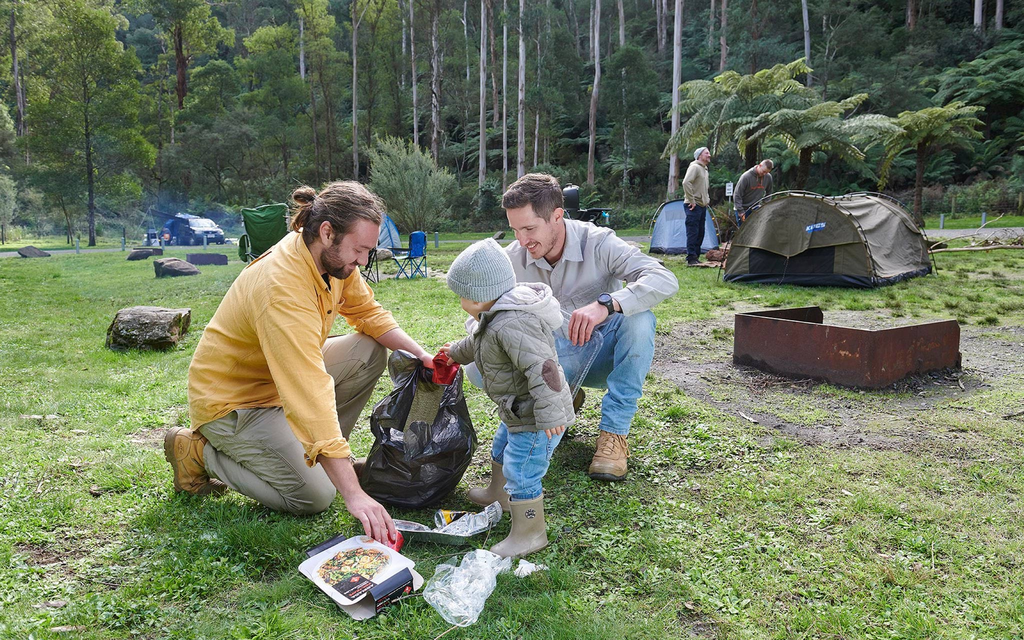 Campers cleaning up rubbish at campsite Campers cleaning up rubbish at campsite