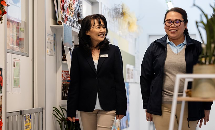 Two educators walking together in a hall way