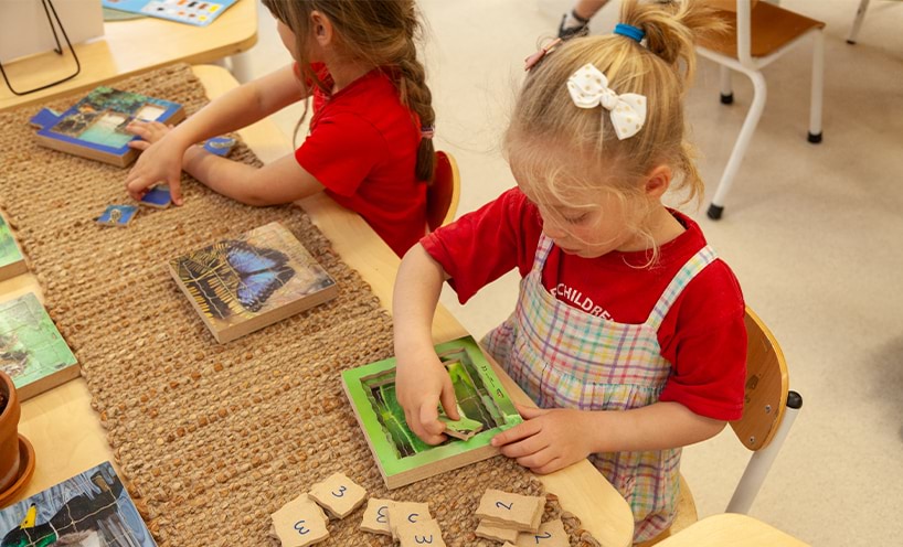 Children playing with a puzzle in a kindergarten room.