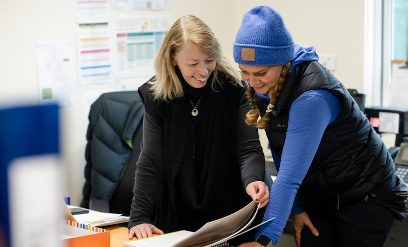 Two educators reading a book together 