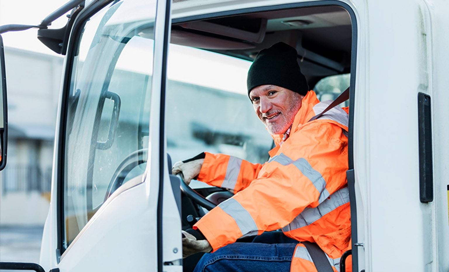 Truck driver sitting in a truck looking at the camera through the door
