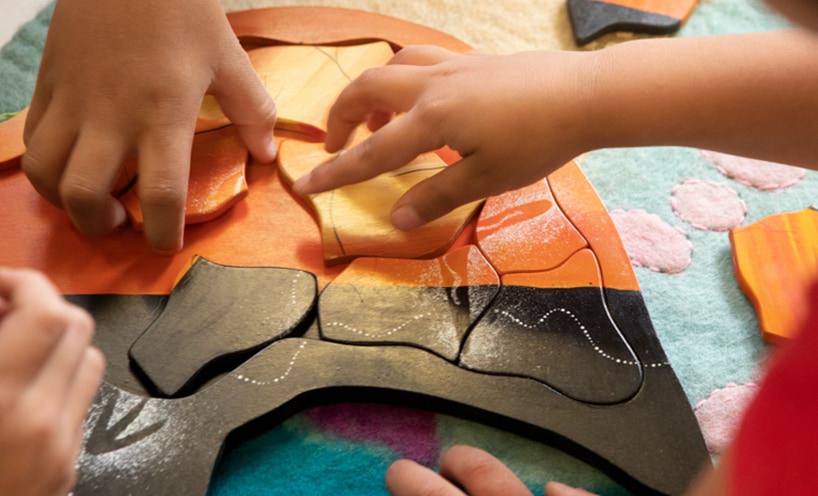 hands arranging the aboriginal Australia wooden puzzle