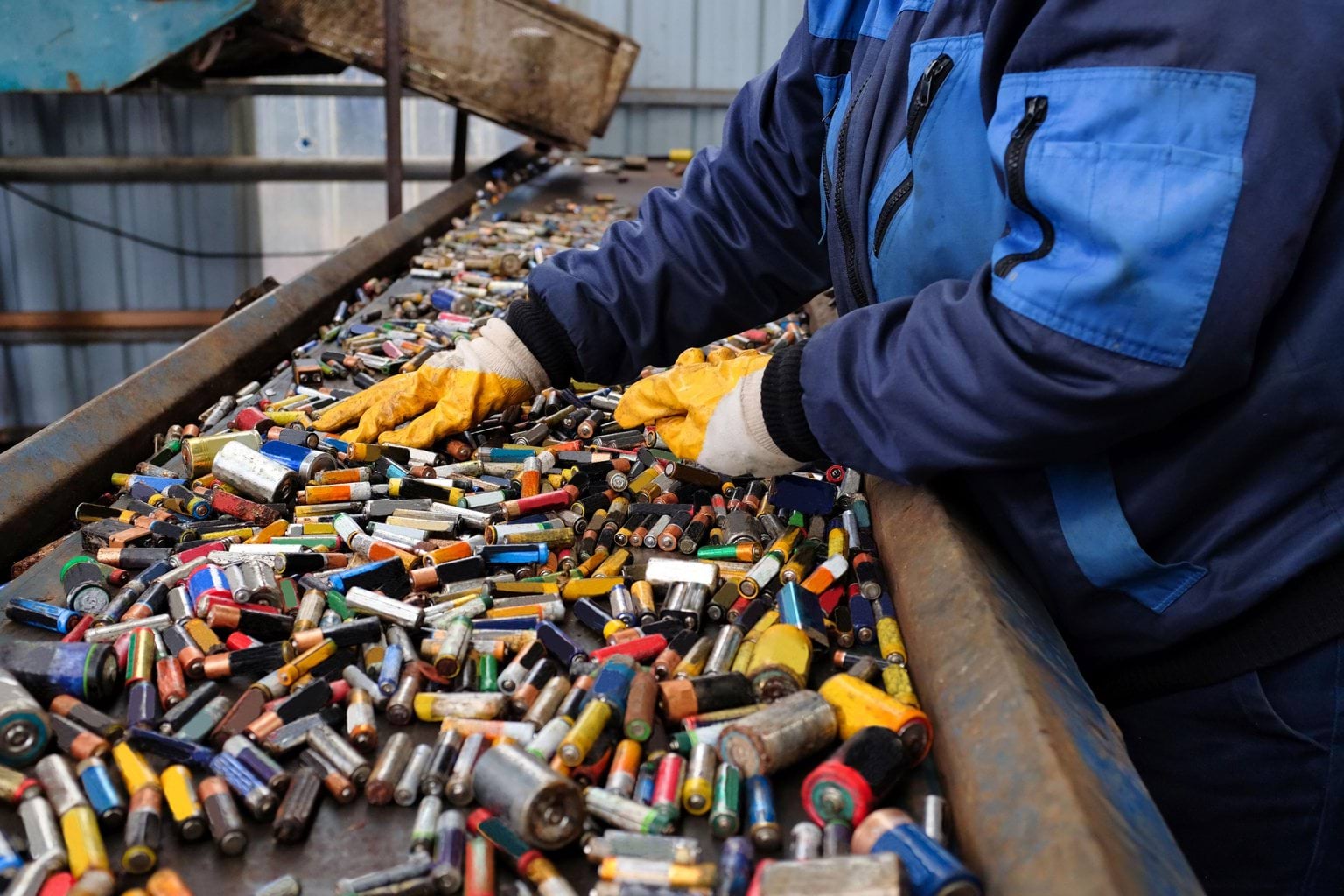 Worker sorting through waste batteries on a conveyor belt
