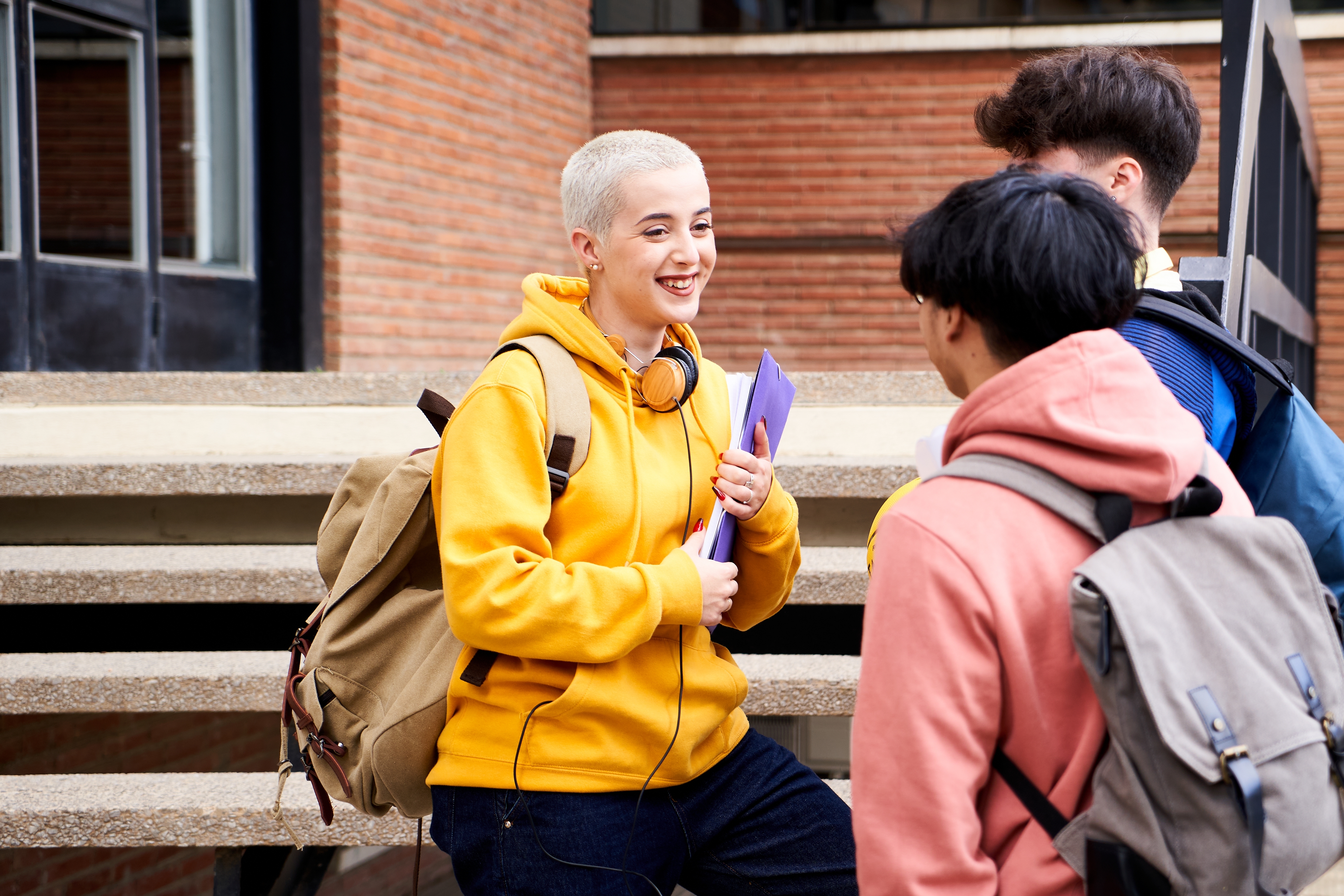 Three students standing outside talking.