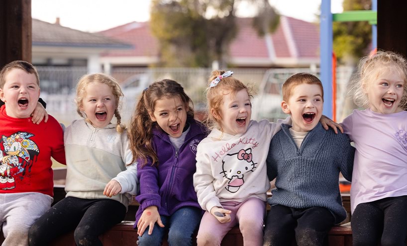 Children sitting in a line and laughing out loud