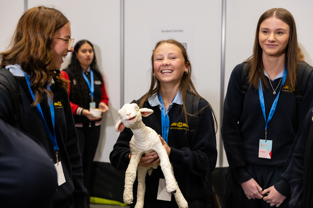Female students holding an artificial lamb from the birthing demonstration