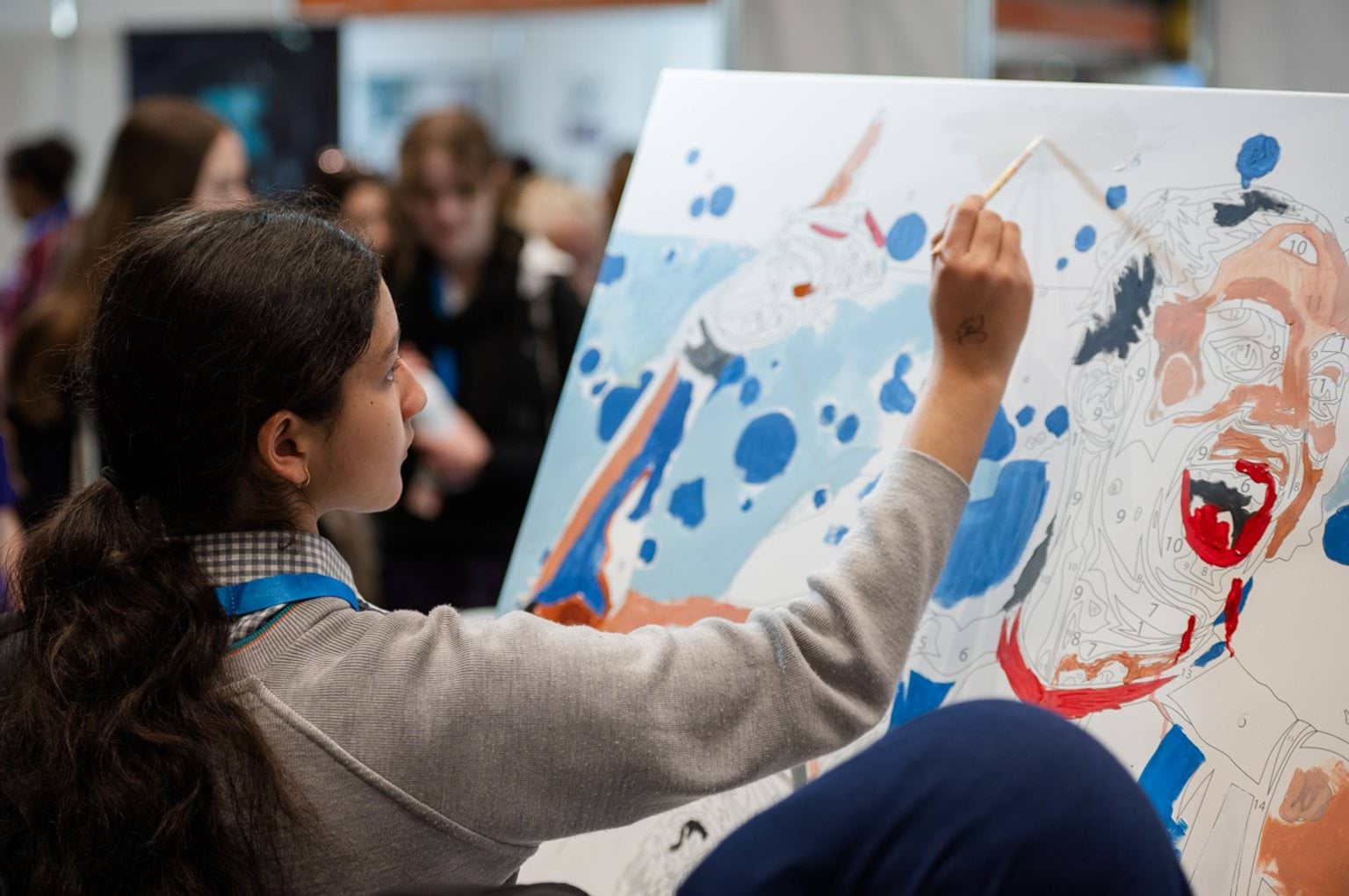 Female student participating in a paint by numbers activity on a communal canvas