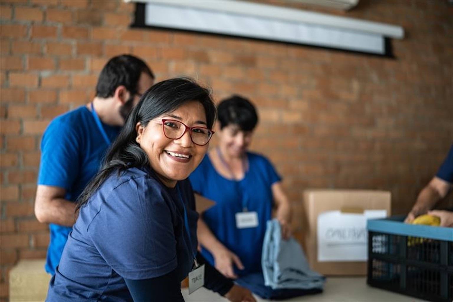 A volunteer in a blue uniform sorting and packing boxes