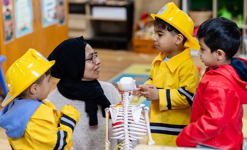 Teacher and 3 small children standing around a small skeleton model..