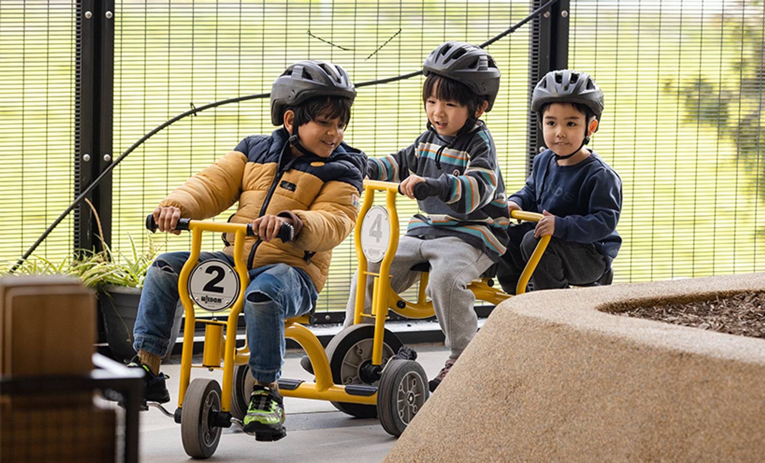 3 small children riding yellow tricycles. 